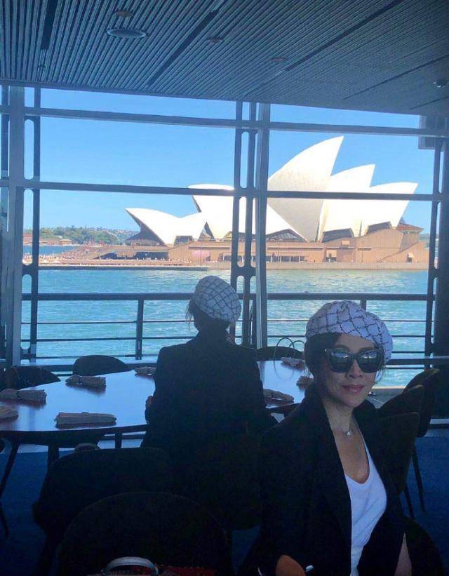 的刘嘉玲或站或坐在海边白色悉尼歌剧院的背景下,感觉非常宁静平和